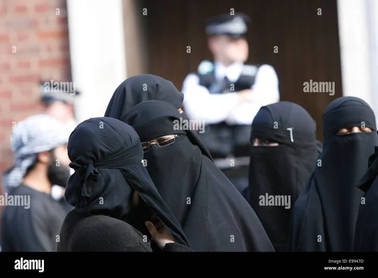 Femmes en niqab dans une rue de Londres, avec un policier en arrière-plan.