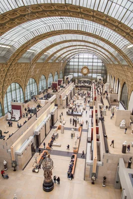 Vue plongeante sur la nef du musée d'Orsay, mettant en valeur son architecture et ses sculptures.