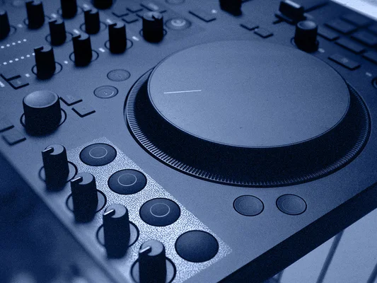 Gros plan d'un contrôleur DJ avec molette et pads de performance, éclairage bleu.