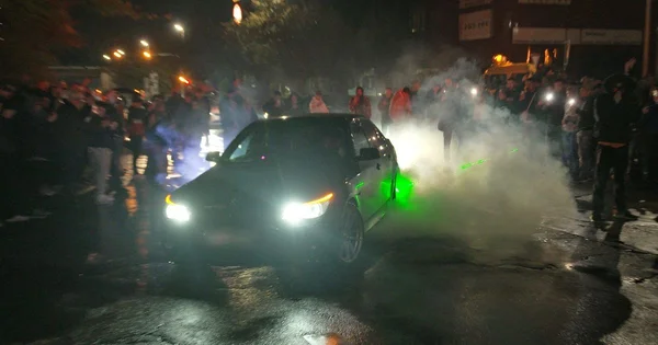 Heurts lors d'un rassemblement illégal de tuning à Bourg-en-Bresse, avec fumée et foule autour d'un véhicule.