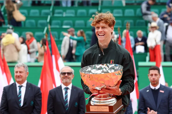 Jannik Sinner pose avec le trophée et des officiels après sa finale gagnante.