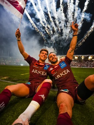 Joueurs de l'UBB célébrant sous un feu d'artifice après un match.