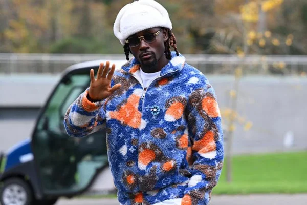 Un joueur des Bleus, coiffé d'un bonnet blanc et d'une veste colorée, salue lors de son arrivée à Clairefontaine.