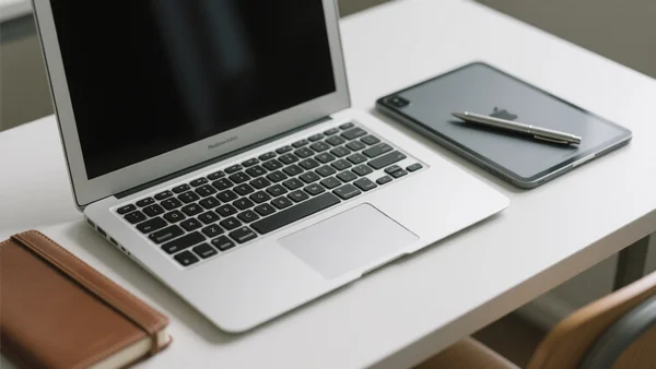 Un MacBook Air et un iPad Pro posés sur un bureau d'étudiant, à côté d'un carnet et d'un stylo, lumière naturelle