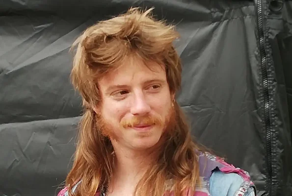 Participant au festival de la coupe mulet, arborant une coiffure et une moustache travaillées.