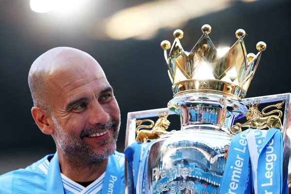 Pep Guardiola posant avec le trophée de la Premier League.