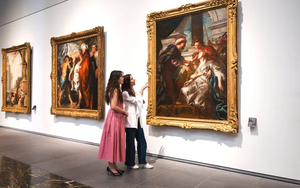 Visiteuses admirant une peinture classique dans une galerie du Louvre Abu Dhabi.