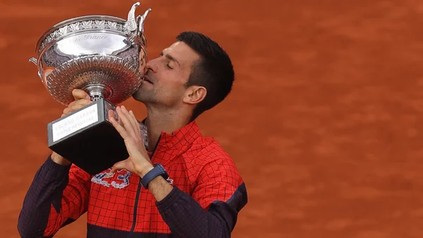 Novak Djokovic célèbre son 23e titre du Grand Chelem en embrassant le trophée sur la terre battue de Roland-Garros.