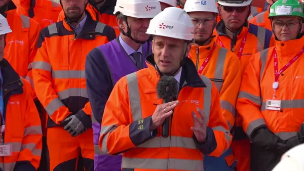 Visite de chantier nucléaire : un responsable en tenue de sécurité s'adresse aux ouvriers.