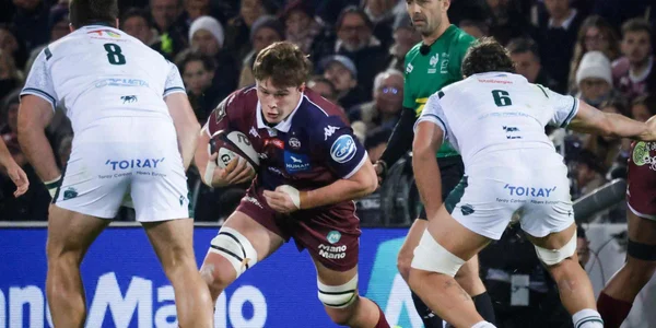 Un joueur de l'UBB en action, entouré d'adversaires.