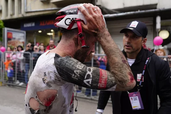 Adam Yates, visiblement blessé et en détresse après une chute, assisté par un membre de son équipe.