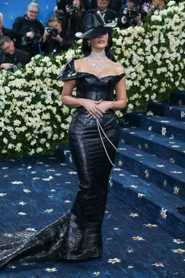 Colman Domingo, Zendaya et Lewis Hamilton sur le tapis rouge du Met Gala 2025, entourés de fleurs blanches et de photographes.