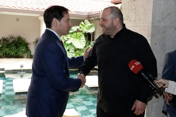 Poignée de main entre un négociateur ukrainien et un représentant américain près d'une piscine à Miami.