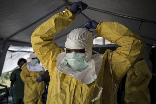 Personnel médical en tenue de protection dans une tente de soins lors de l'épidémie d'Ebola.