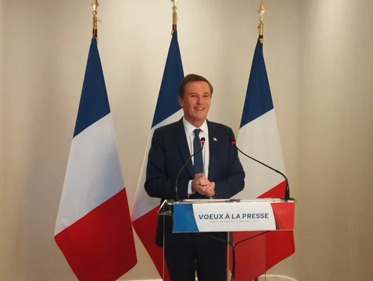 Nicolas Dupont-Aignan s'adressant à la presse devant les drapeaux français.