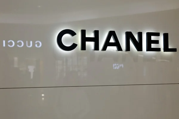 Façade d'une boutique Chanel, avec le logo illuminé et le reflet de Gucci.