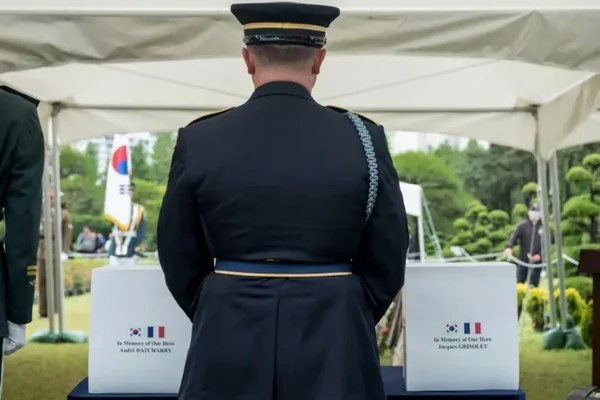 Hommage militaire devant les plaques commémoratives des deux vétérans français, ornées des drapeaux français et sud-coréen.