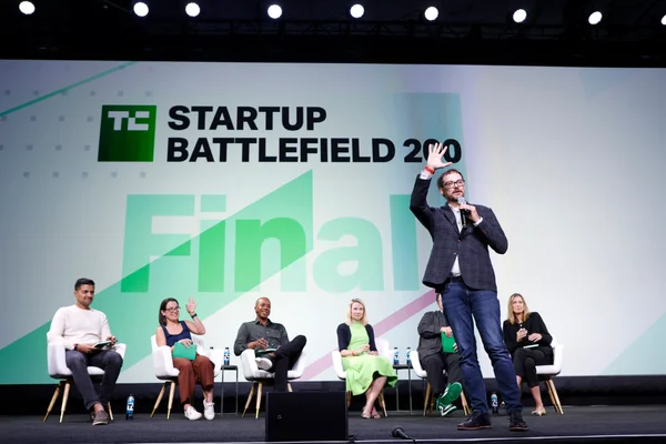 Un participant s'adressant au public lors de la finale du Startup Battlefield 200, entouré des autres finalistes.