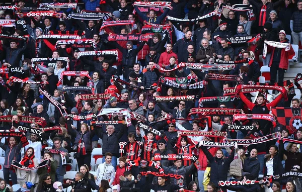 Supporters de l'OGC Nice en tribune, agitant des écharpes du club.