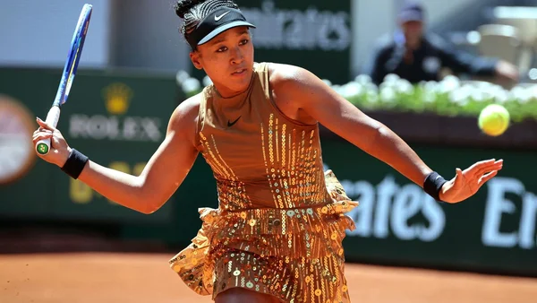 Naomi Osaka, dans une tenue scintillante dorée, en plein échange sur le court Suzanne-Lenglen.