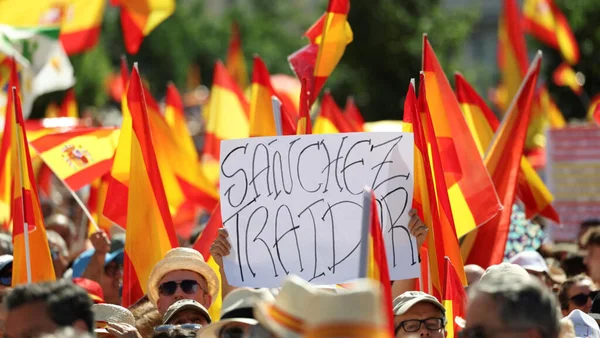 Manifestants à Madrid brandissant des drapeaux espagnols et une pancarte accusant Pedro Sánchez de trahison.
