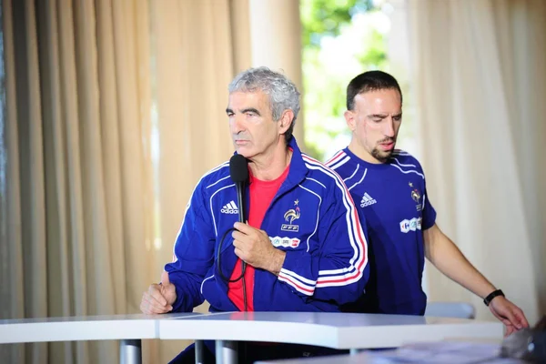 Raymond Domenech s'exprimant au micro dans un survêtement de l'équipe de France.