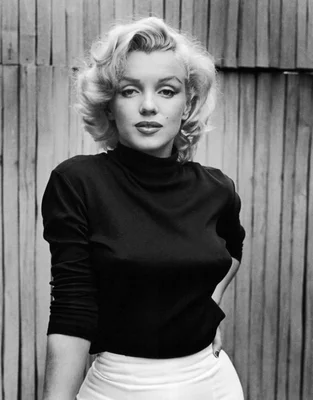 Marilyn Monroe élégante en col roulé, photographiée devant une clôture en bois.