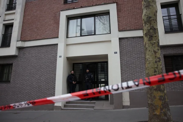 Des policiers devant un immeuble parisien bouclé par un ruban de police.