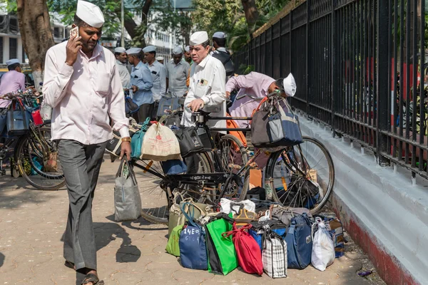 Dabbawalas de Bombay réunis sur un trottoir avec leurs vélos chargés de tiffins.