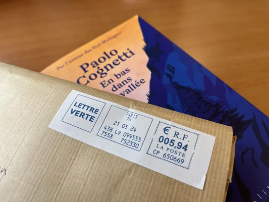 Colis postal avec étiquette Lettre Verte devant un livre de Paolo Cognetti.