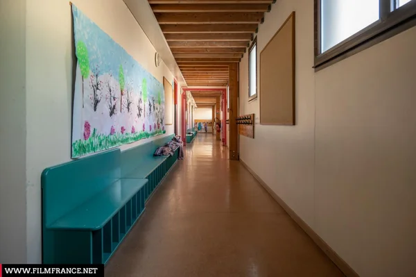 Couloir d'école primaire vide, avec des dessins d'enfants aux murs.