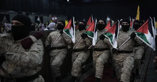 Rassemblement de combattants pro-iraniens tenant des drapeaux palestiniens.