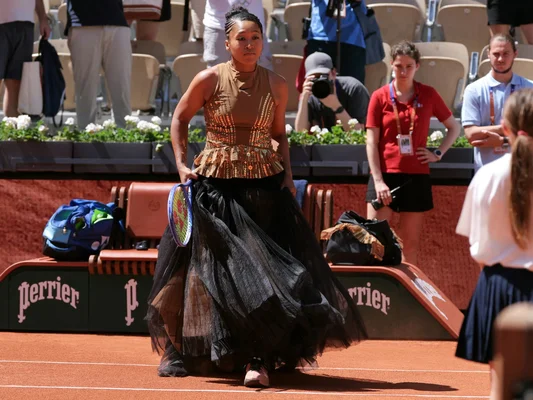 Naomi Osaka dans une tenue dorée et noire lors de son entrée sur le court Suzanne-Lenglen.