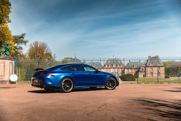 Mercedes-AMG GT hybride rechargeable bleue garée devant un manoir.