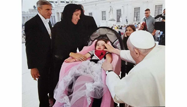 Le pape François bénit une fillette dans une poussette.