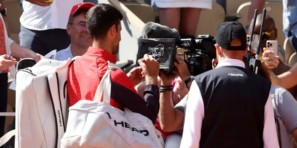 Novak Djokovic interagit avec un caméraman sur le court de Roland-Garros.