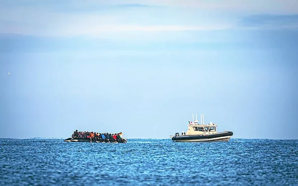 Canot surchargé de migrants à côté d'un bateau de patrouille blanc lors d'une tentative de traversée de la Manche.
