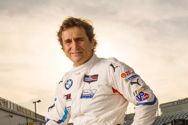 Alex Zanardi posant en combinaison de course blanche sous un ciel couvert.
