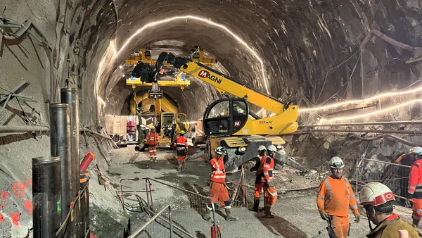 Ouvriers sur le chantier Lyon-Turin, avec un télescopique Magni jaune.