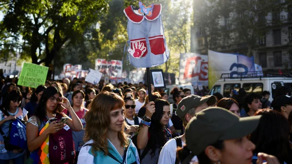 Manifestation pour l'université publique avec une foule dense et un vêtement d'enfant brandi comme symbole.