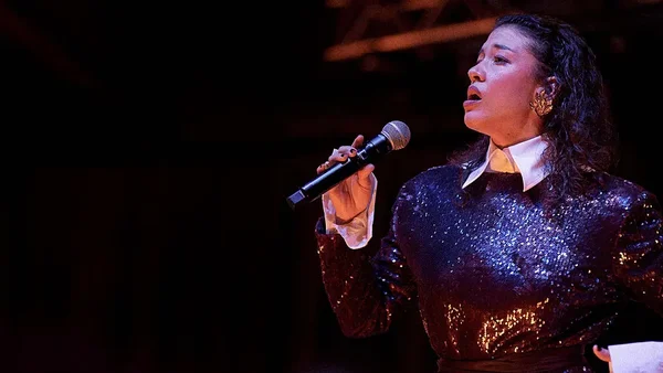Gildaa en concert, concentrée sur son chant, dans une ambiance tamisée.