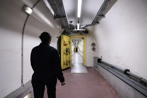 Couloir souterrain de la base militaire du mont Verdun, près de Lyon, avec une porte blindée jaune.