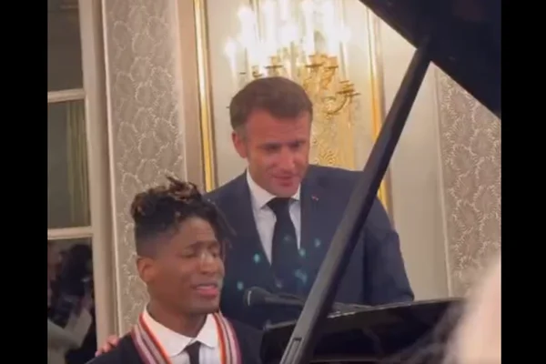 Emmanuel Macron debout derrière un pianiste, lors de la reprise de « La Bohème » de Charles Aznavour.