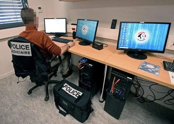 Un officier de la police judiciaire travaille sur des ordinateurs lors de l'enquête sur les cyberattaques contre des fédérations sportives.