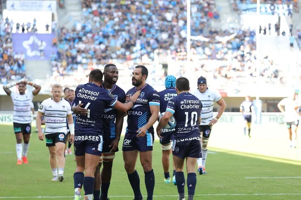 Joueurs de Montpellier Hérault Rugby célébrant une victoire au stade.