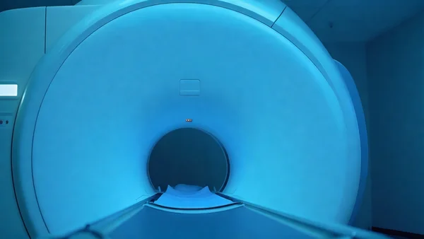 Vue rapprochée d'une IRM dans un hôpital, lumière bleutée, cylindre blanc massif au centre de la pièce