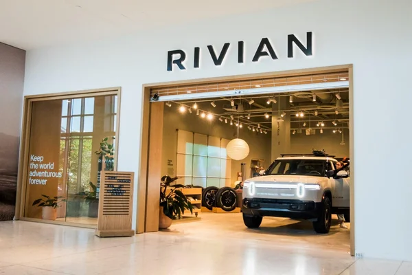 Showroom Rivian avec un SUV électrique blanc exposé et le logo de la marque.
