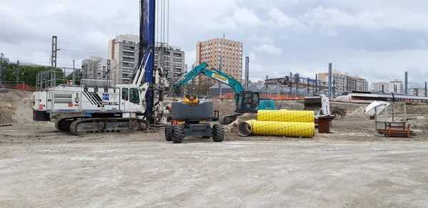 Engins de chantier du CDG Express dans le 18e arrondissement, avec foreuse et pelleteuse près de tuyaux jaunes.