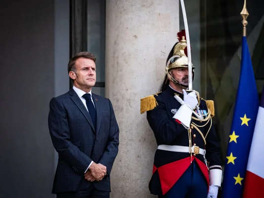 Emmanuel Macron aux côtés d'un soldat en uniforme d'apparat lors d'une cérémonie à l'Élysée.