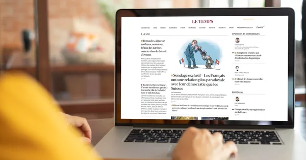 Un lecteur consulte l'édition numérique française du journal Le Temps sur son ordinateur portable.